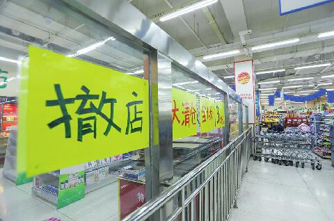 22日,沃尔玛泉城路店外围商铺挂出"撤店"招贴,超市仍在正常营业.